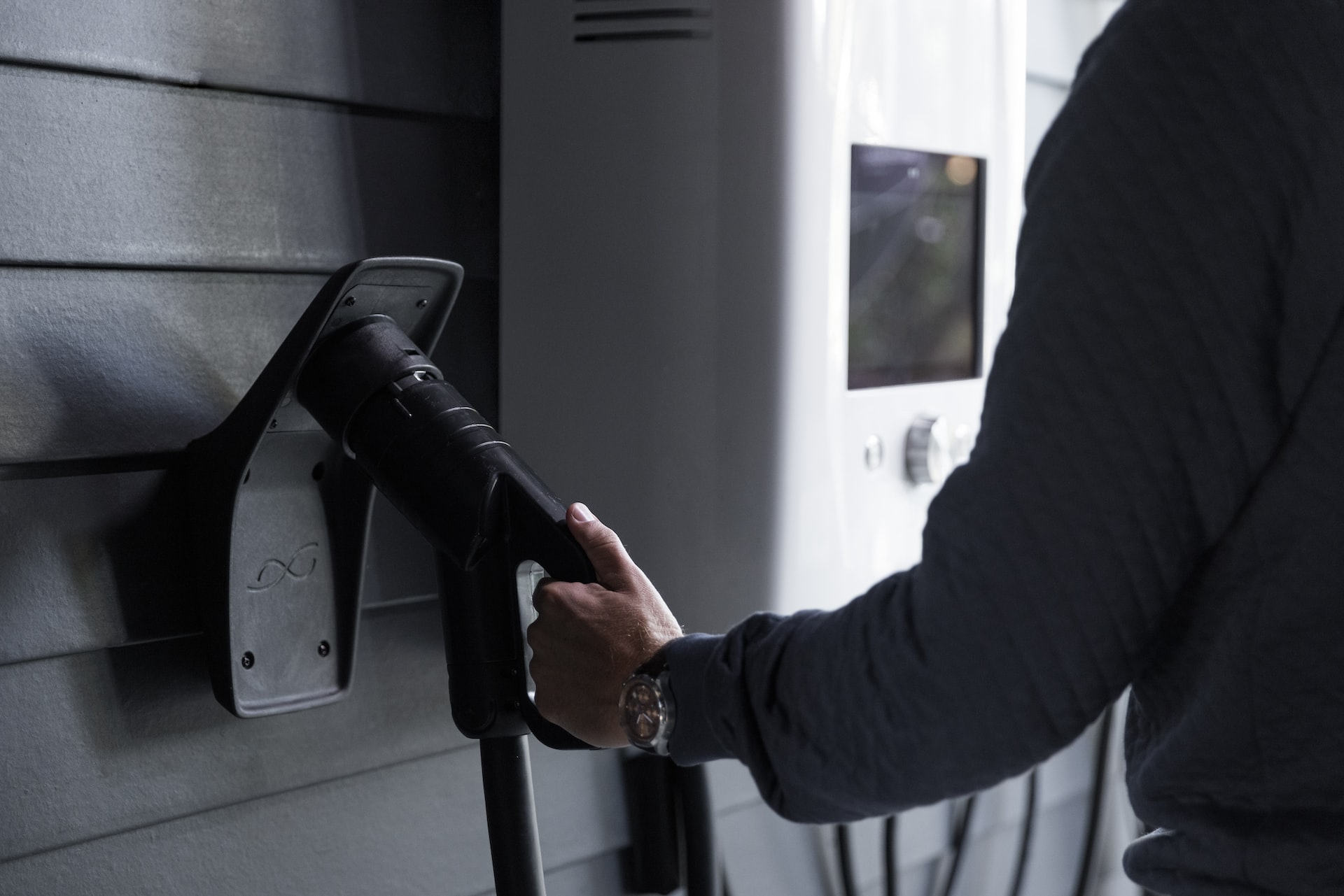 An electric car charger hooked to the wall of a garage.