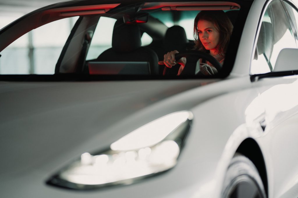 Woman holding the steering wheel of the electric car.