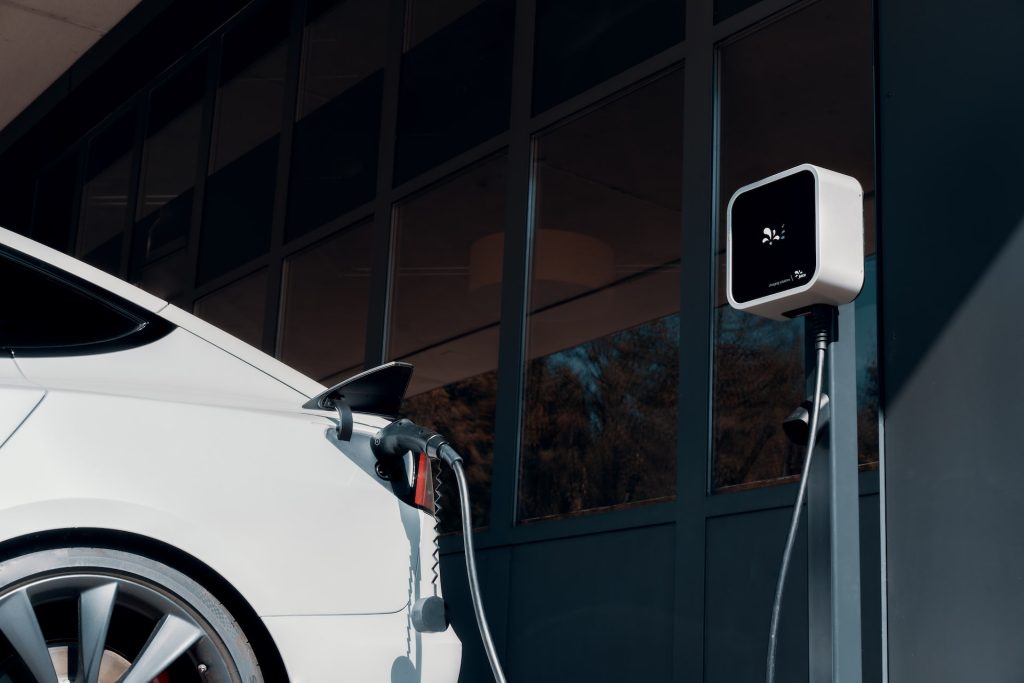 A white car charging at a garage charge point.