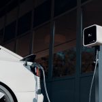 A white car charging at a garage charge point.