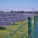 Solar panels near a fence, harnessing renewable energy source.